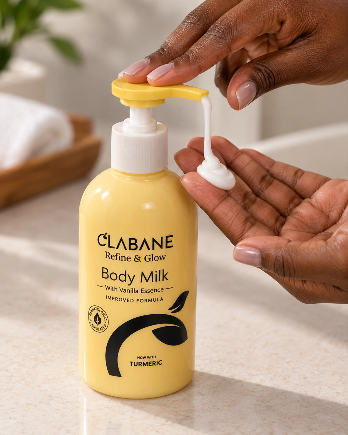 A bottle of Clabane Body Milk with Vanilla Essence being dispensed with a hand on a bathroom counter. The bottle is a warm yellow with a white pump and a yellow flip-top cap, and the brand name 'CLABANE' is clearly visible on the front.