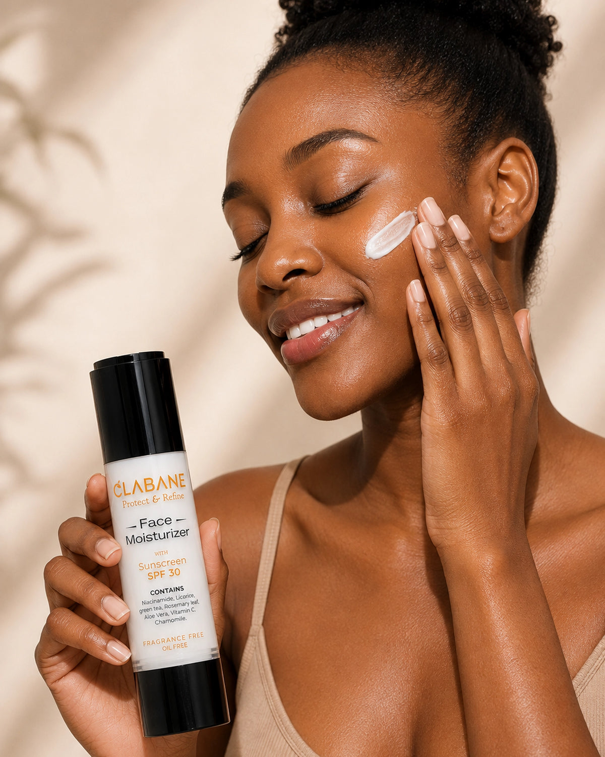 A woman applies white face moisturizer to her cheek while holding a bottle of Clabane Face Moisturizer SPF 30. The bottle is white with a black cap, and the background is a warm beige with soft leaf shadows.