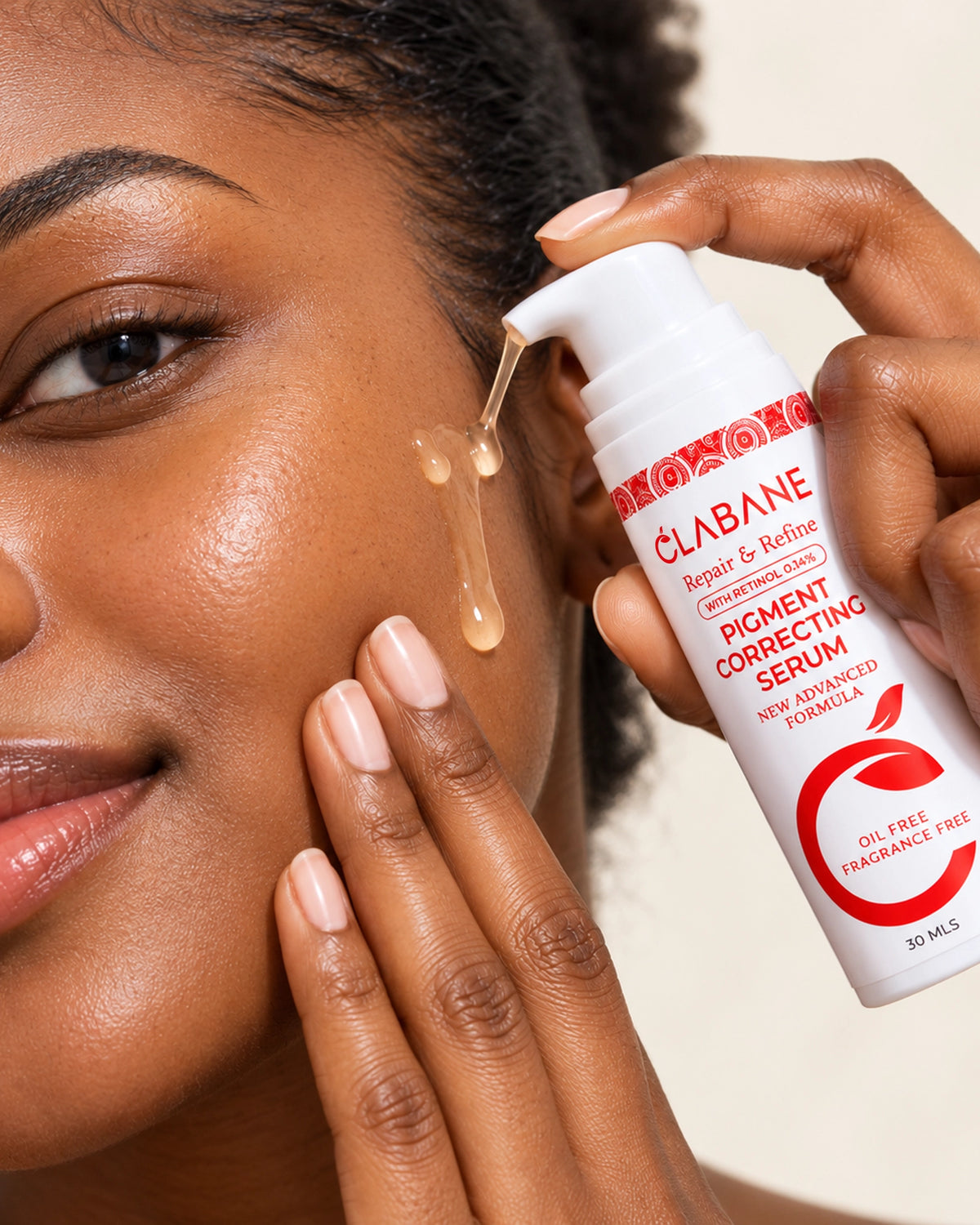 A close-up lifestyle shot of a woman applying Clabane Pigment Correcting Serum, with the white and red pump bottle held to her cheek as a golden serum is being absorbed.